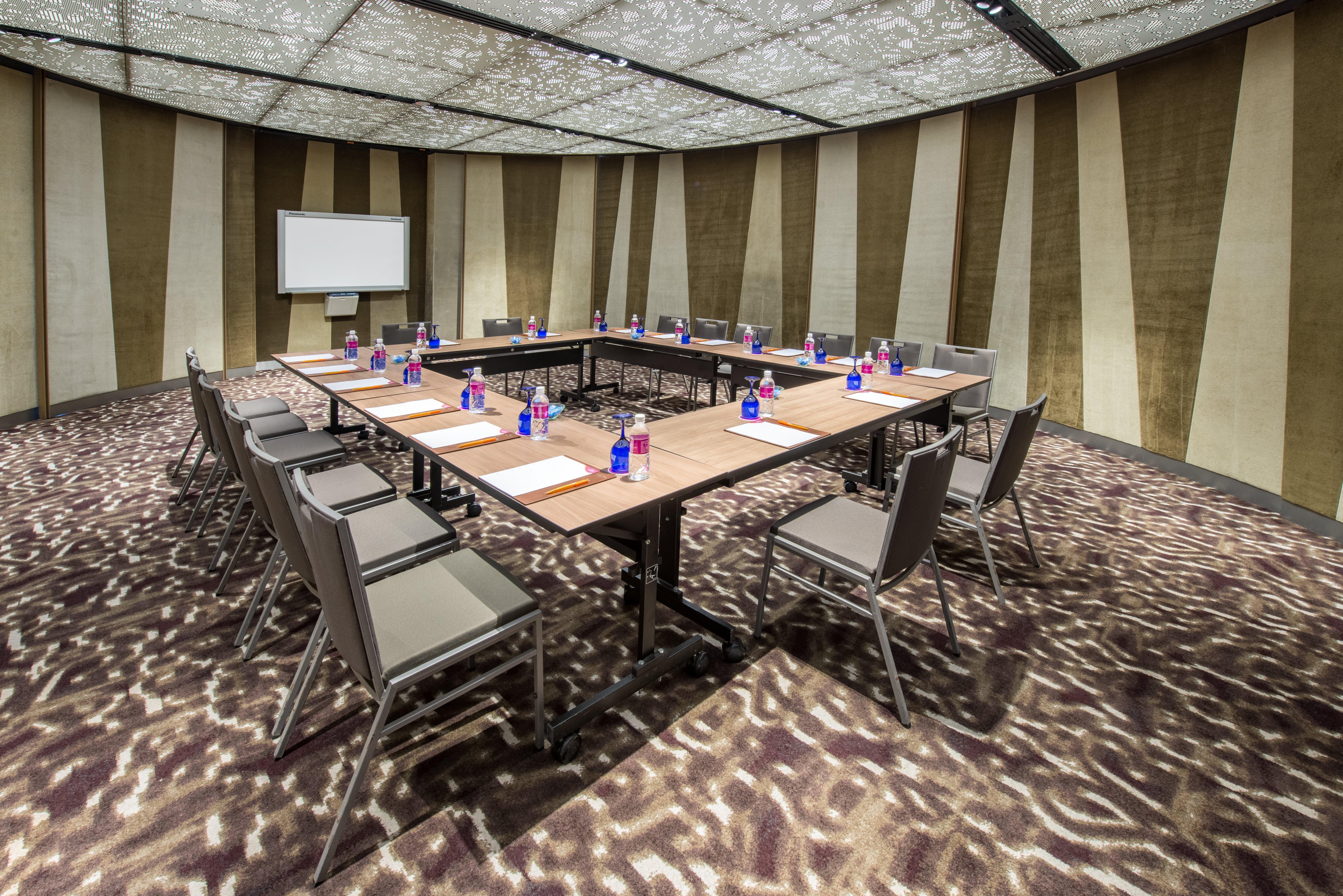 Crowne Plaza Changi Airport, An Ihg Hotel Singapore Exterior photo The photo depicts a conference room set up for a meeting. There is a large rectangular table in the center with chairs arranged around it. Each seating area has a small bottle of water and a notepad, suggesting it's prepared for attendees. The room f