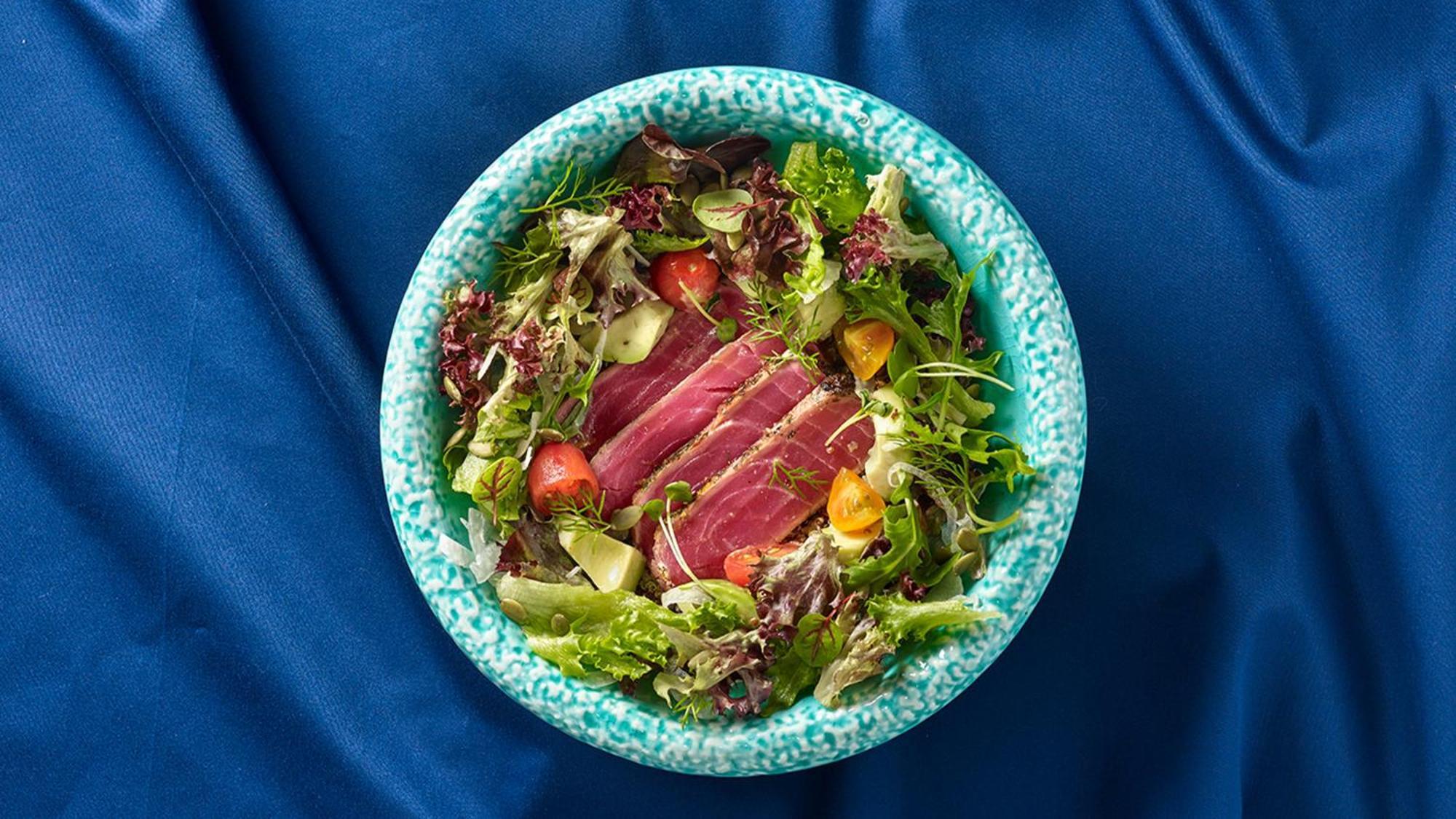 Crowne Plaza Changi Airport, An Ihg Hotel Singapore Exterior photo The photo shows a bowl of salad featuring a variety of fresh leafy greens, including different types of lettuce. There are sliced pieces of seared tuna placed over the salad, adding a protein element. The salad is garnished with cherry tomatoes and p