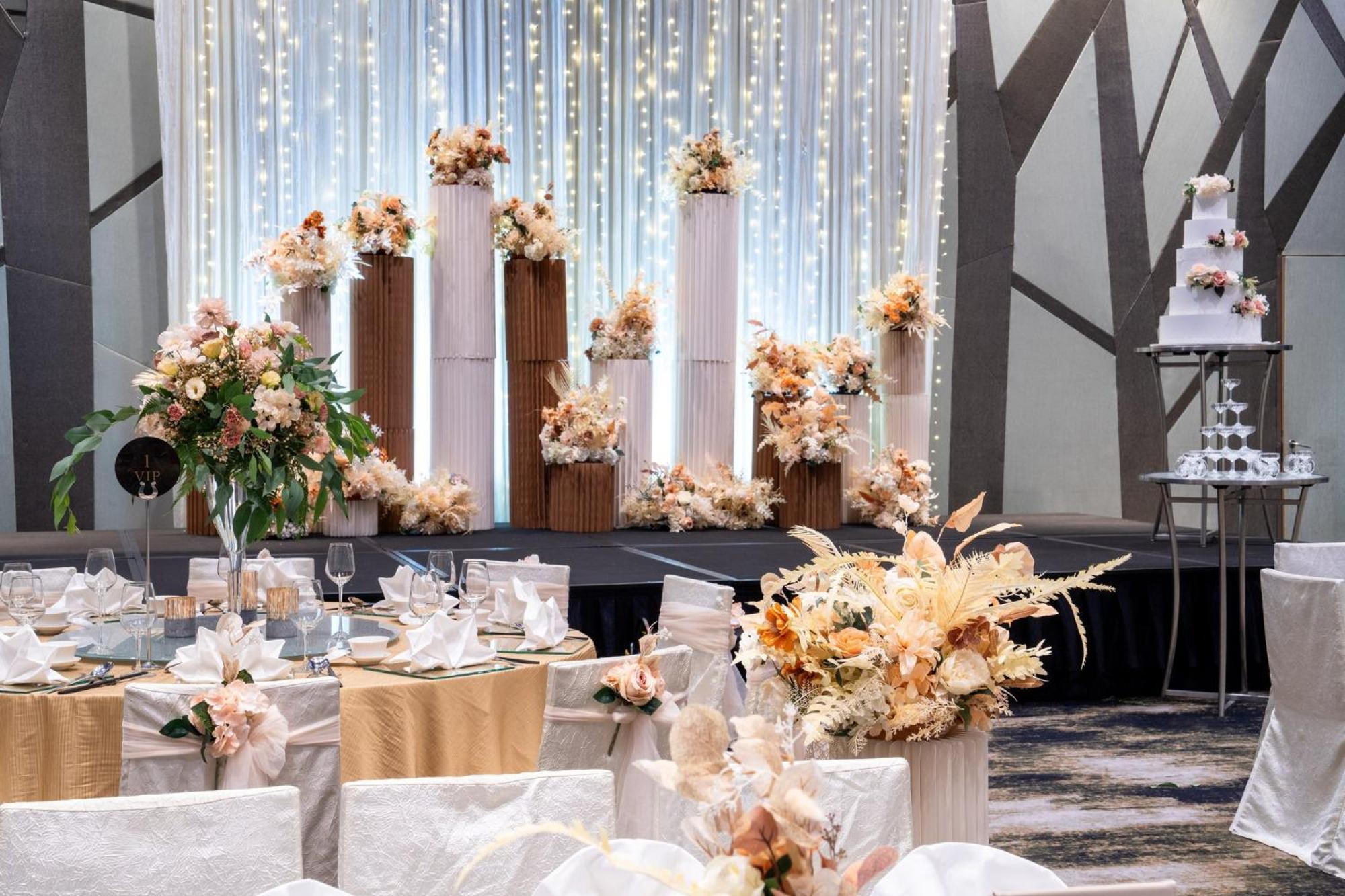 Crowne Plaza Changi Airport, An Ihg Hotel Singapore Exterior photo The photo shows an elegantly decorated wedding reception. In the background, there are tall columns adorned with floral arrangements in soft, pastel colors. These floral displays are complemented by string lights hanging above, creating a romantic am