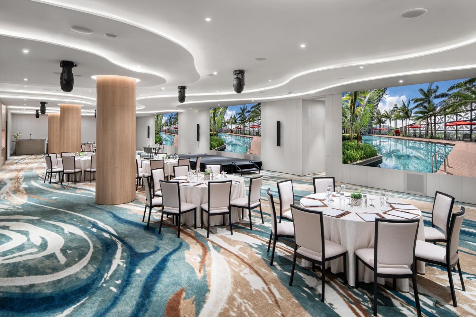 Crowne Plaza Changi Airport, An Ihg Hotel Singapore Exterior photo The photo showcases a modern event space or dining area. It features several round tables covered with white tablecloths and set with dishes and utensils. The floor has an eye-catching design with swirling patterns in various shades of blue and beige